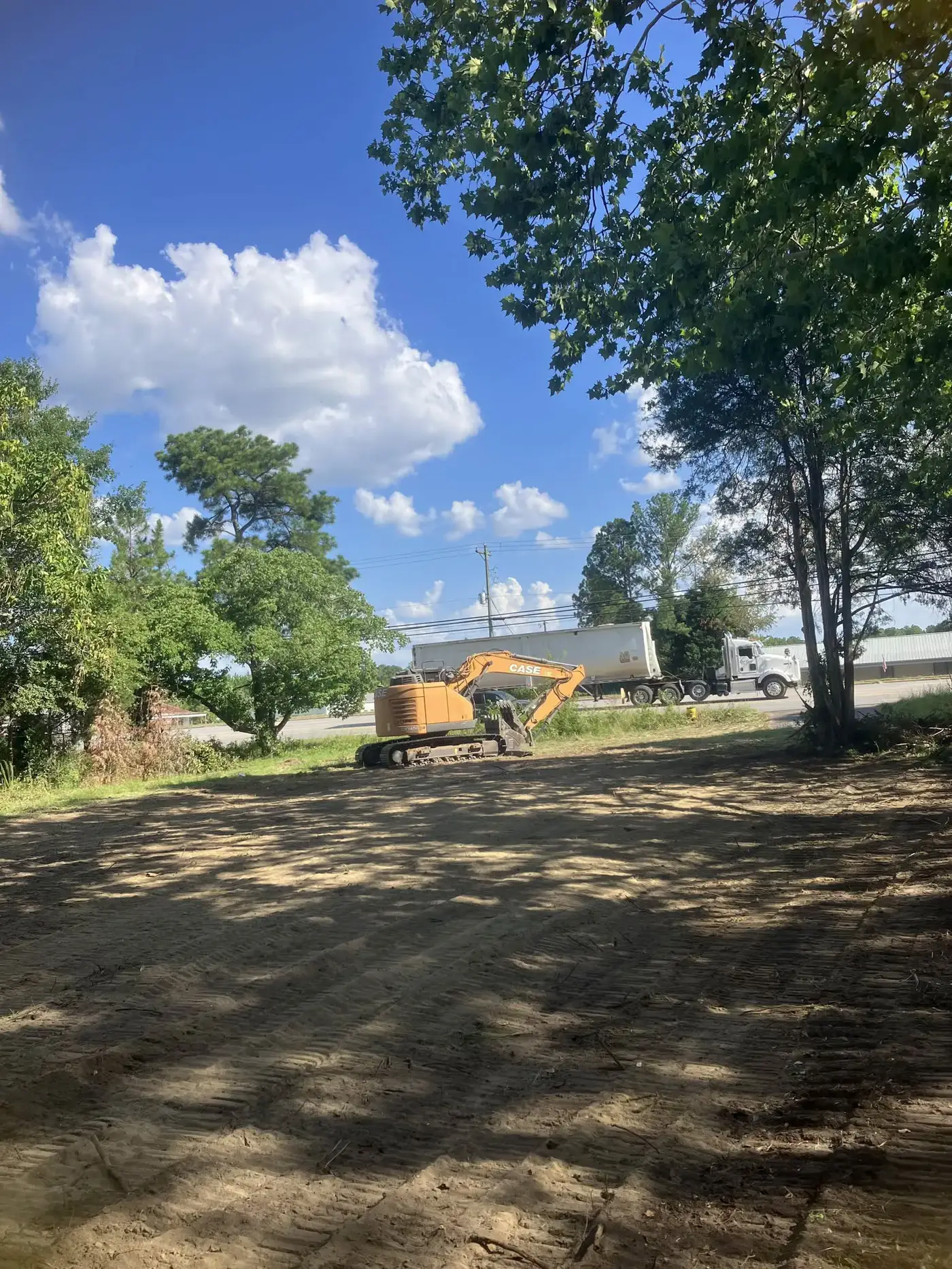 Dirt Cheap CASE excavator and tri axle dump trailer on a cleared lot