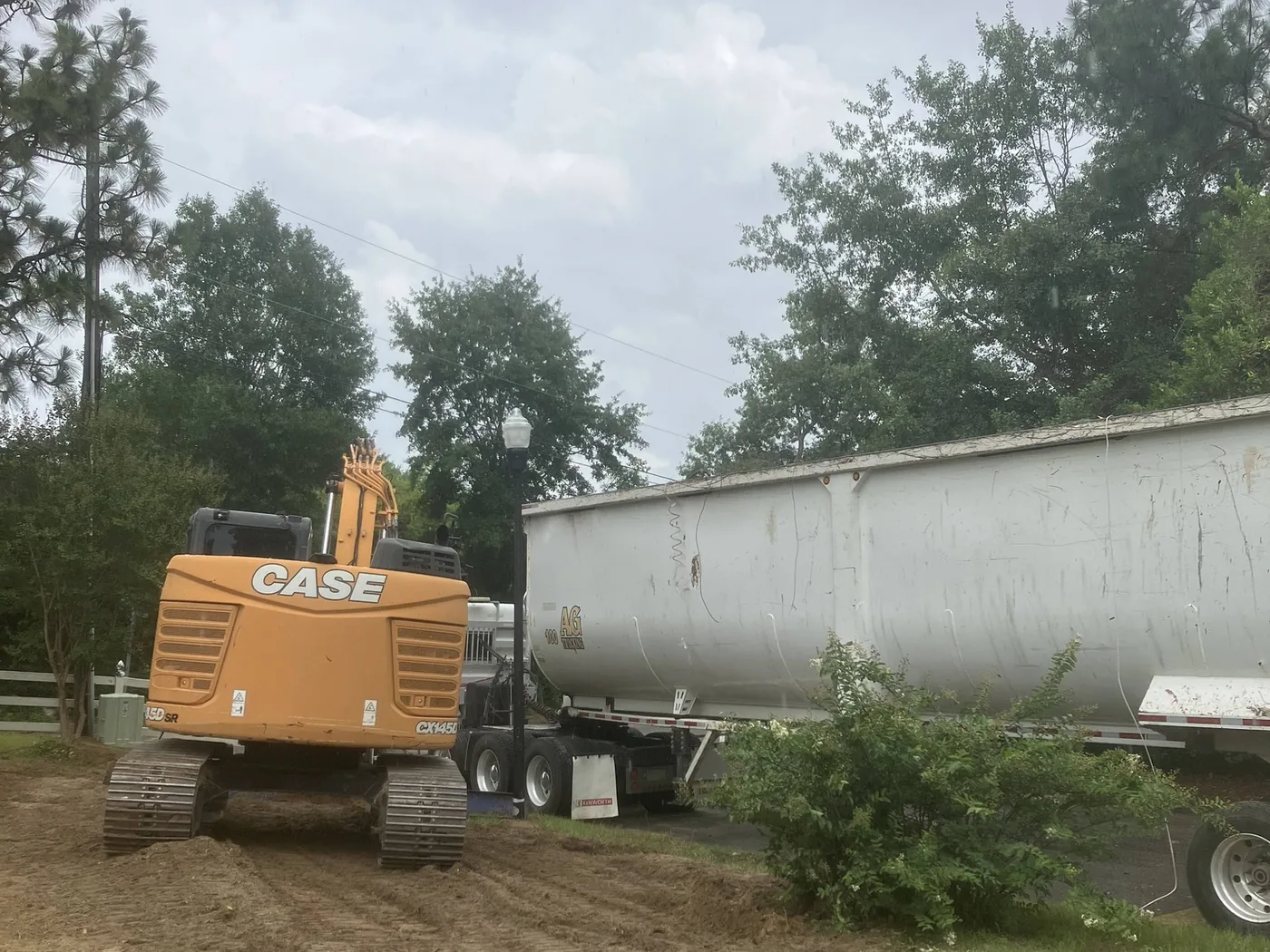 CASE excavator and an empty dump trailer pulled onto the lot for a mobile home teardown
